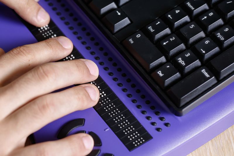 Zwei Hände auf einer Brailletastatur