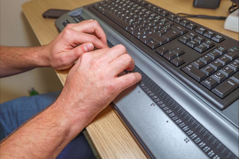 Hände auf einer Braillezeile am Arbeitsplatz