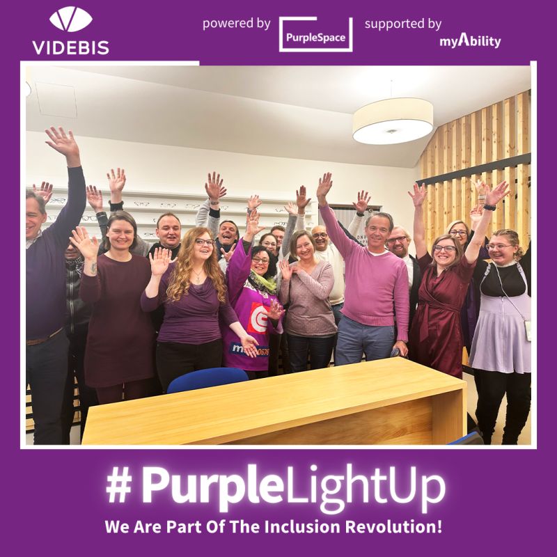Das VIDEBIS Team mit violetter/lila Kleidung wirft freudig die Arme in die Luft