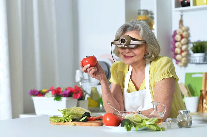 Eine Dame kocht mit der elektronischen Lupenbrille Jordy