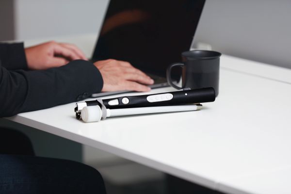 Herr mit WeWalk SmartCane 2 im Büro am Tisch zusammengeklappt
